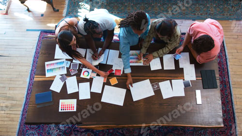 Preview: Overhead View Of Team Having Creative Design Meeting Around Wooden Table In Office