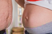 Vorschau: Bauch der schwangeren Frau. Mann und schwangere Frau zeigen ihren Bauch. Seitenansicht.Das Konzept von