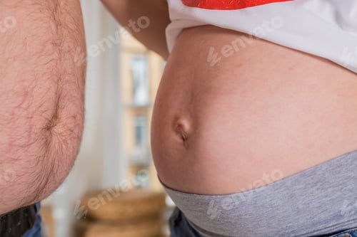 Preview: Belly of pregnant woman. man and pregnant woman is showing their bellies.side view.The concept of