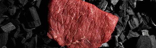 Preview: panoramic shot of raw beef sirloin on small coal pieces