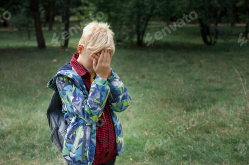 Preview: The boy covered his face with his hands sad and upset because he is being bullied at school and at h