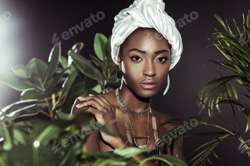 Preview: fashionable african american woman in white wire head wrap behind leaves