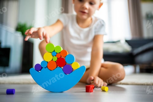 Preview: Little girl playing with wooden balancing toy on the floor in home living room. Focus on balancer