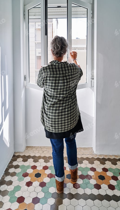 Preview: Middle-aged woman closing the window in a room with colored hydraulic flooring