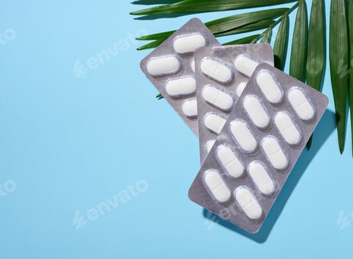 Preview: Oval white pills in a gray blister pack on a blue background, top view. Copy space