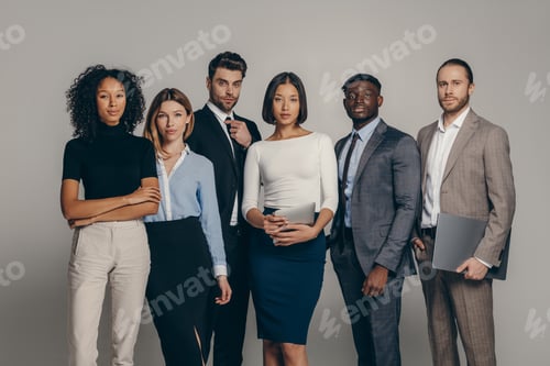 Preview: Confident young business team looking at camera while standing on beige background together