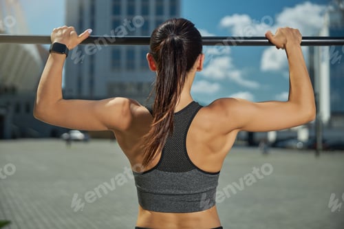 Preview: Back view of sporty girl pulling up on bar