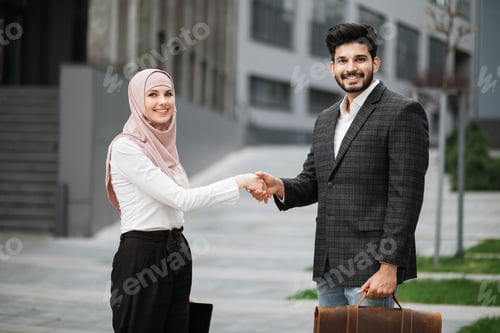 Preview: Arabian man and woman shaking hands for successful deal