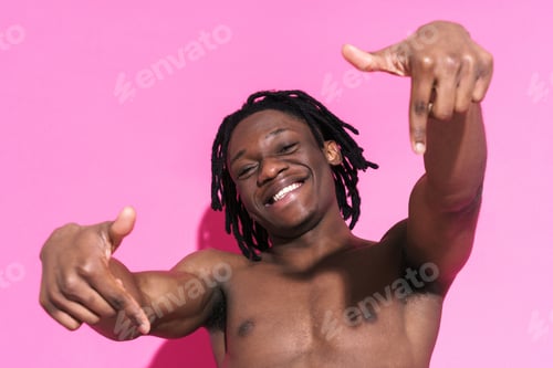 Preview: Black shirtless man smiling while pointing fingers downward