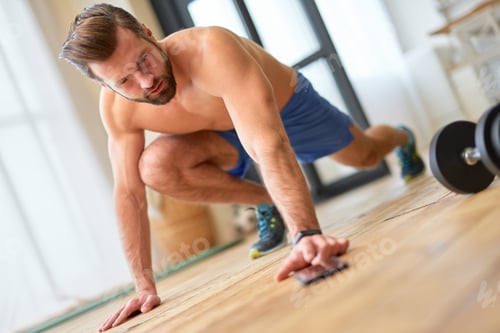 Preview: Athletic young man using smartphone during home workout