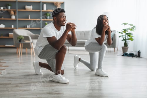 Preview: Happy African American couple doing forward lunges at home