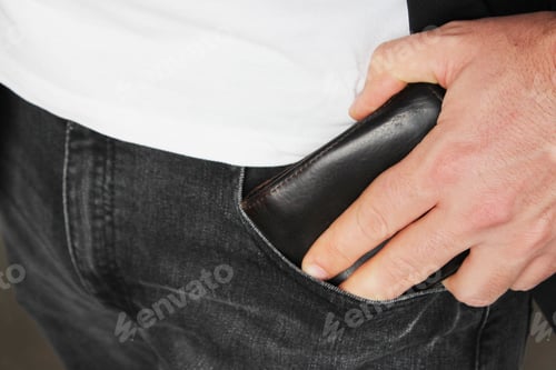 Preview: Closeup shot of a person putting a leather wallet in his pocket
