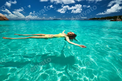 Preview: Woman In Yellow Bikini Lying On Water At Tropical Beach