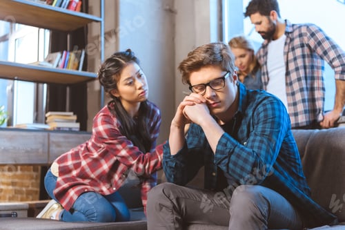 Preview: Young asian woman supporting male friend in depression, other people on background
