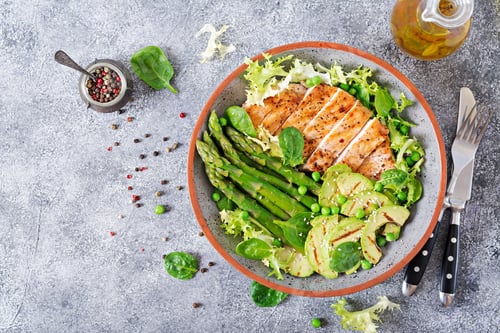 Vista previa: Filete de pollo cocinado a la parrilla con una guarnición de espárragos y aguacate a la plancha.