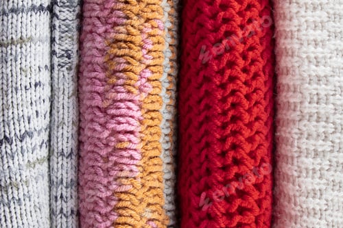 Preview: Stack of warm knitted sweaters. Autumn concept. Woolen jumpers and maple leaf on a wooden background