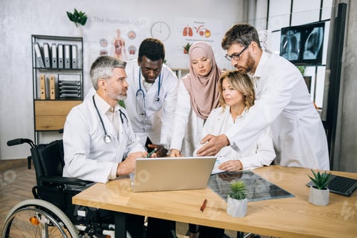 Preview: Multicultural qualified doctors using laptop during meeting