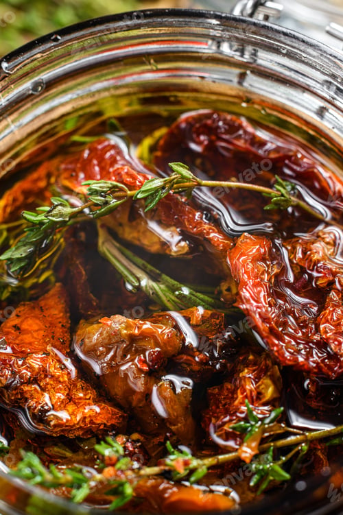 Preview: Sun dried tomatoes with herbs and salt in olive oil in a glass. Gray background. Top view