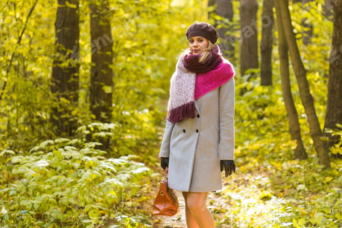 Preview: Fall, nature and people concept - Young beautiful woman in grey coat standing in autumn park