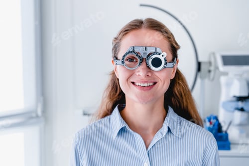 Preview: Smiling young female patient checking up sight using ophthalmic glasses