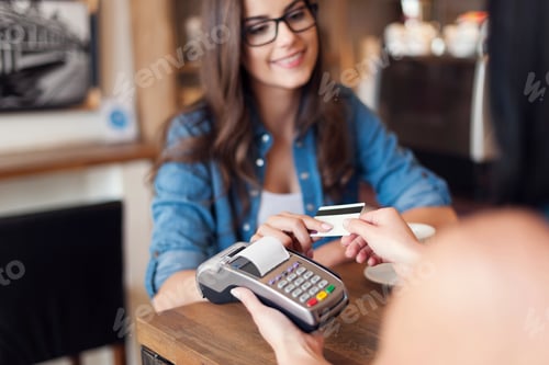Preview: Smiling woman paying for coffee by credit card