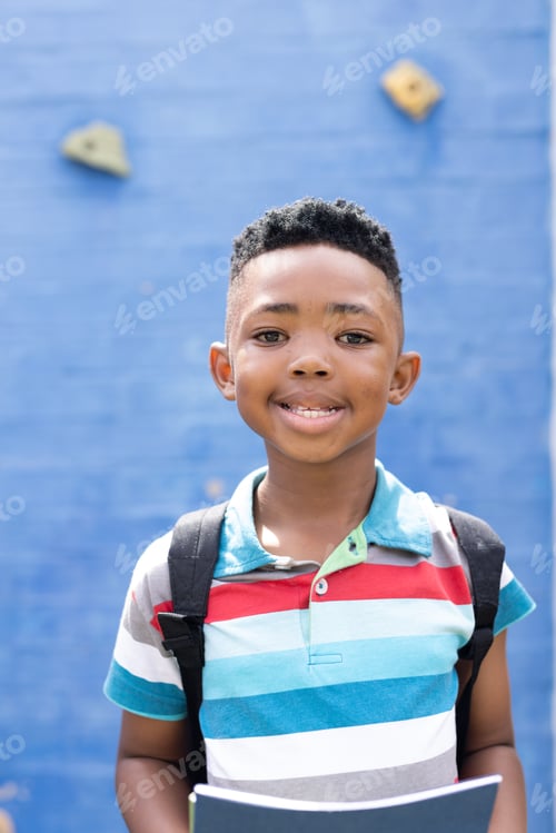 Preview: Vertical portrait of smiling african american boy in elementary school playground, copy space