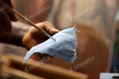 Preview: Talented artist cleaning the paintbrush on a piece of denim fabric