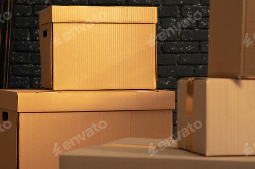 Preview: Stack of cardboard boxes in the empty room against black brick wall