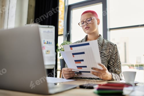 Preview: A focused bald woman analyzes business reports in a modern office space during daytime hours