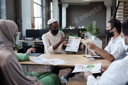 Preview: Group of young economists discussing document by table