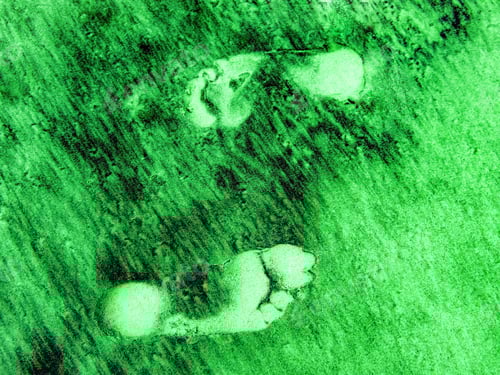 Preview: Two footprints in the green and black colored sand to symbolize environmental protection standards