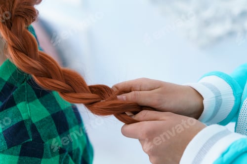 Preview: A friend is braiding a braid for a red-haired girl.