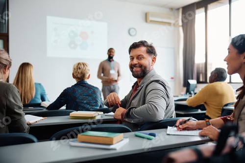 Preview: Happy mature man on education training class in lecture hall looking at camera