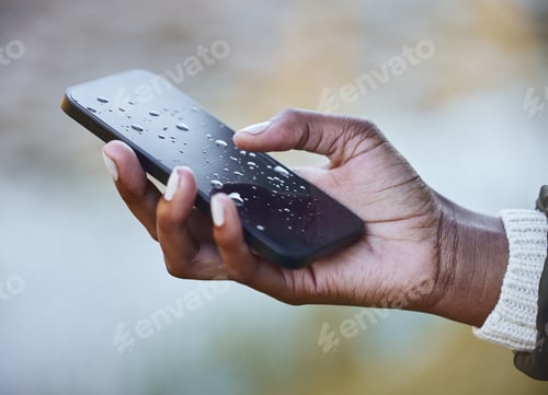 Preview: Water damage is so costly to repair. Shot of a woman holding a wet phone during a camping trip.
