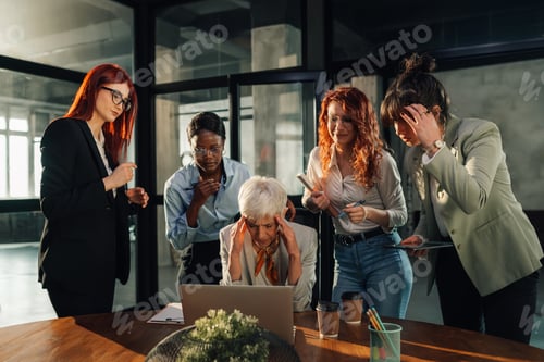 Preview: Disappointed old businesswoman having headache while team looking at laptop.