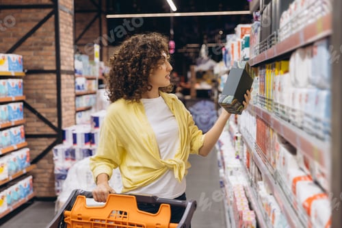 Preview: Woman choosing products pushing shopping cart in supermarket