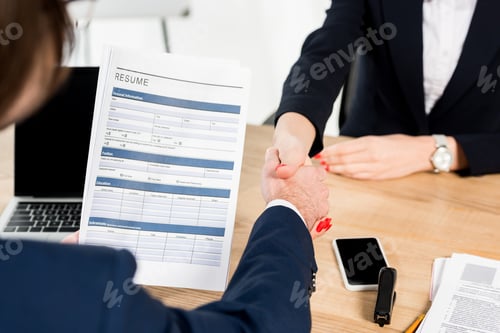 Preview: cropped view of recruiter and employee shaking hands in office