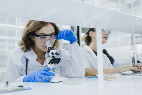 Preview: female researcher, medical scientist or doctor working and checking sample of virus using microscope