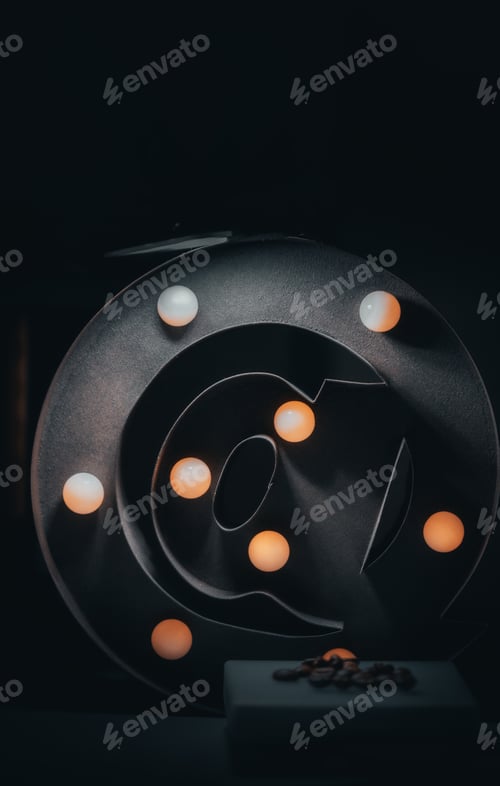 Vista previa: Vertical shot of light bulbs on a big at sign on a black background