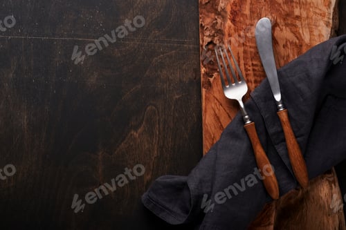 Preview: Vintage silverware. Rustic vintage set of wooden spoon and fork on wooden platter on black wooden ba