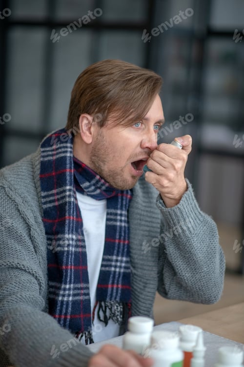 Preview: Man wearing scarf applying inhalator after having attack