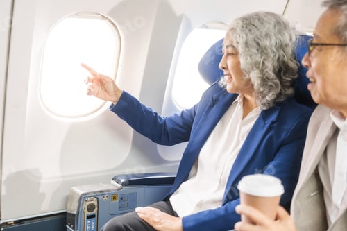 Preview: A mature couple enjoys a plane ride, seated near the window. They gaze out at the sky, savoring