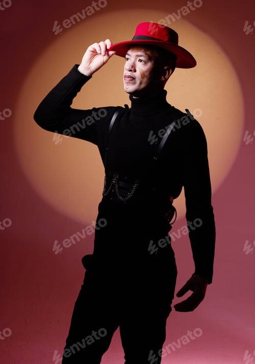 Preview: Fashion, style and man with vitiligo in a studio with a grungy, edgy and goth outfit with an orange