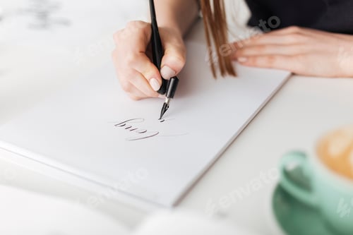 Preview: Close up photo of woman hands holding pen and writing beautiful notes on paper isolated