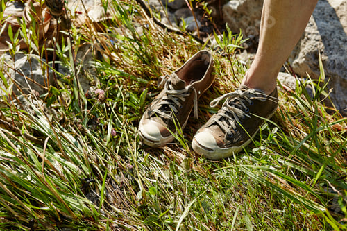 Preview: Cropped view of woman standing on one leg wearing trainers