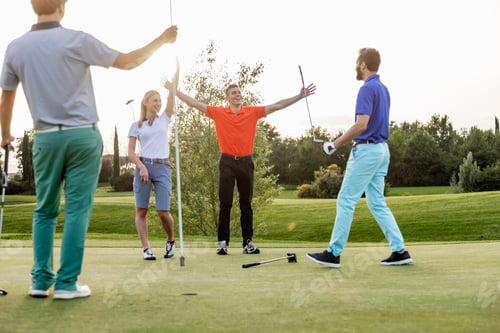 Preview: Friends celebrating a successful putt on the golf course at sunset.
