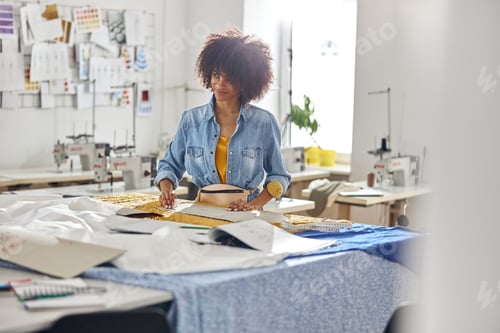 Preview: Stylish African-American lady draws pattern on fabric using tailors chalk in modern workshop