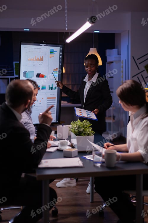 Preview: Businesswoman with dark skin explaining financial graphs using presentation monitor