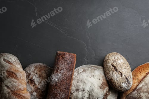 Preview: Different kinds of delicious bread on black table, flat lay. Space for text