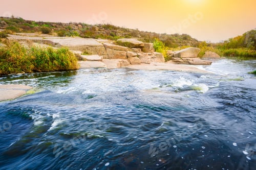 Preview: A small shining stream flows among smooth wet and dark stones